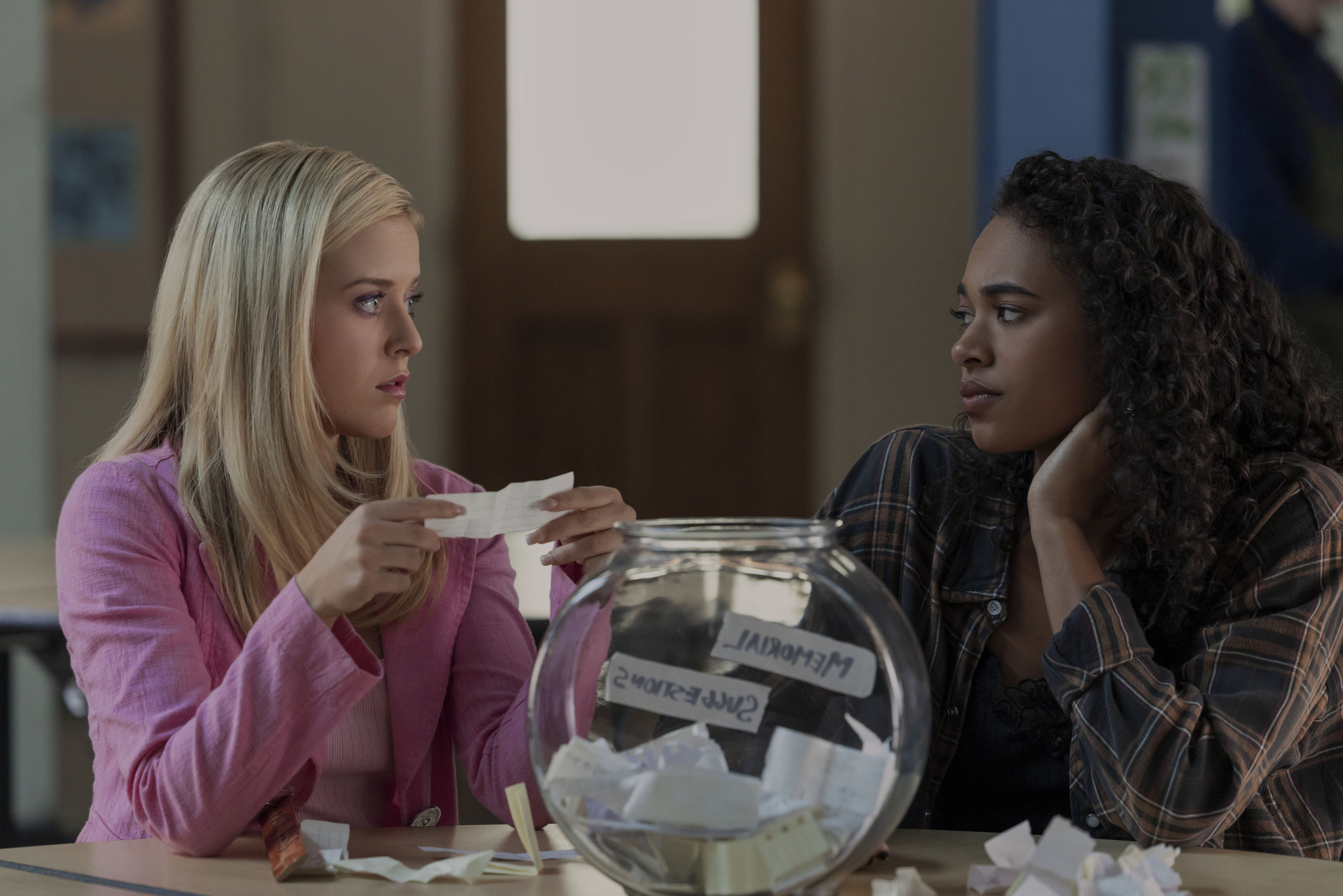 Lexi Minetree as elle and Chandler Kinney pulling paper out of a fish bowl talking at school in a still from elle