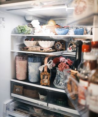 A fridgescaped fridge with vases, bowls, and bottles inside of it