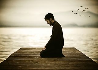 Muslim man fasting Ramadan and praying on beautiful lake.