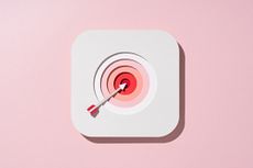 Multi-layered paper craft arrow in shades of white and pink with a bullseye target on red