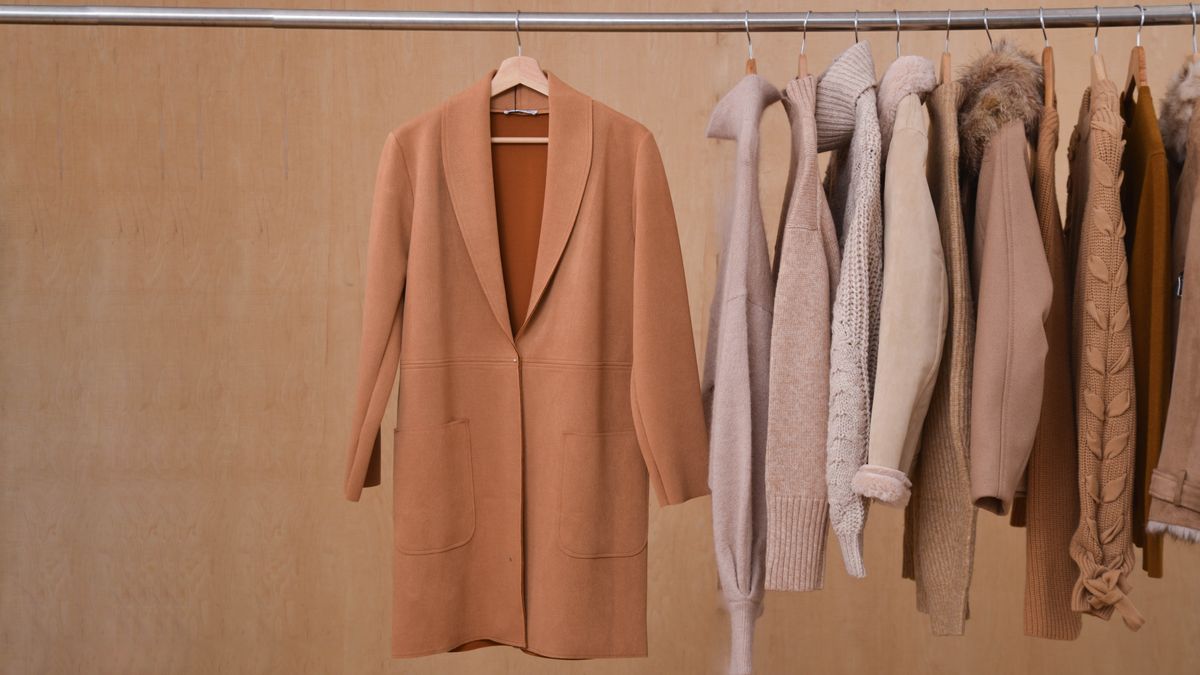 A rack of clothes with a beige coat facing front