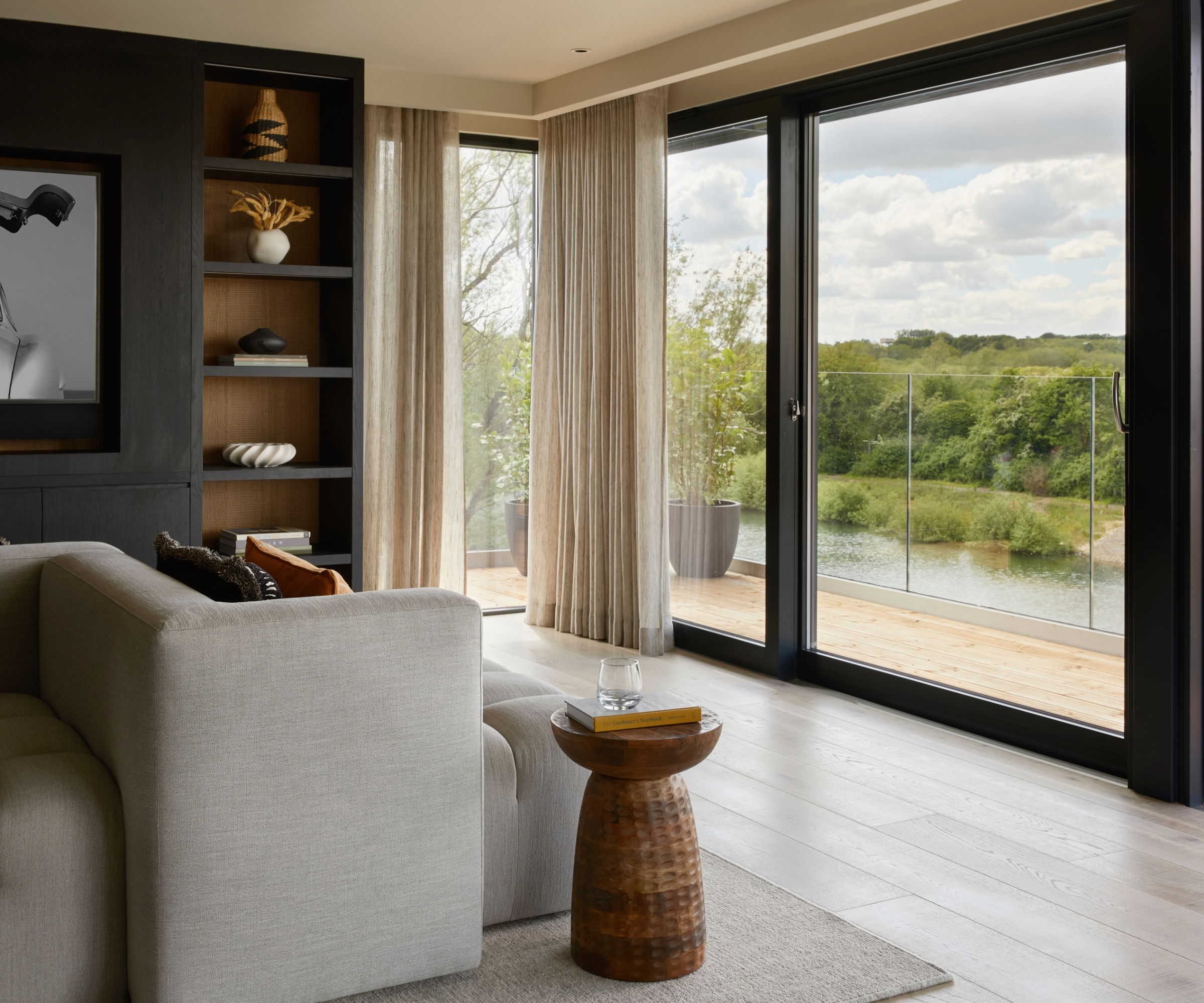 living room with pale wood engineered flooring in front of large sliding black framed patio doors