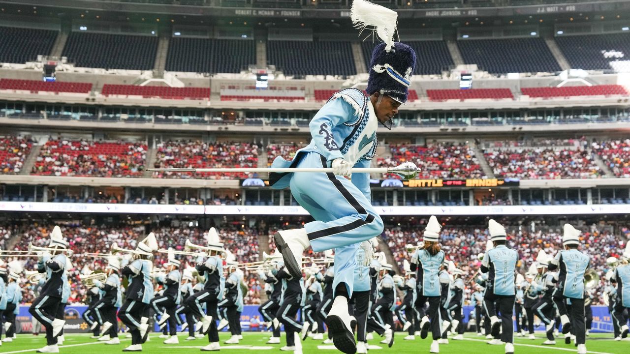 A drum major wearing a blue uniform jumps on the field during the 2024 Pepsi National Battle of the Bands