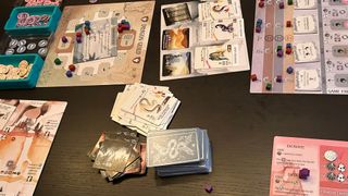 A collection of Wyrmspan cards on a wooden table, in between boards and tokens