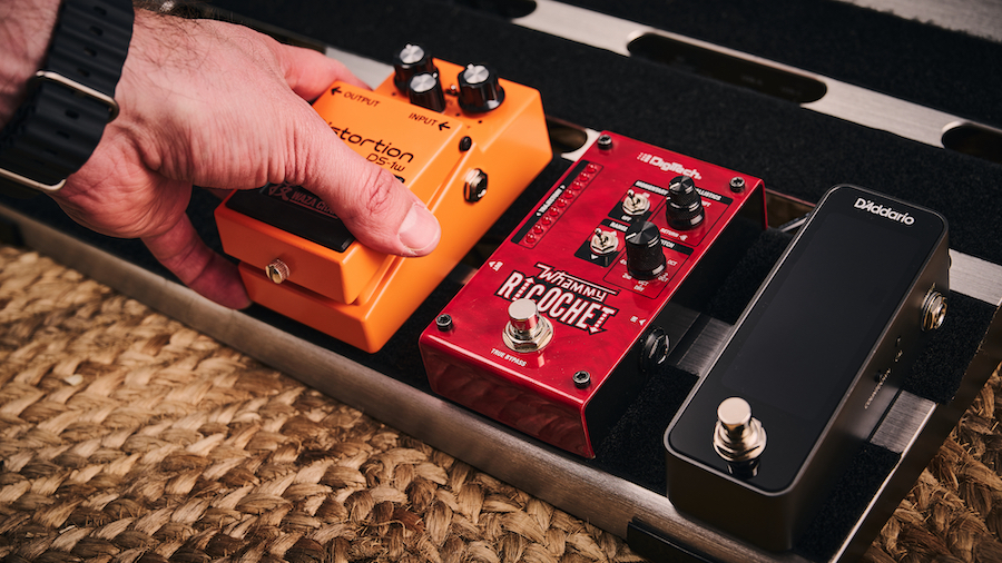 Man placing a Boss pedal on a pedalboard