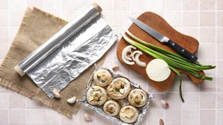 Aluminum foil next to cutting board and vegetables