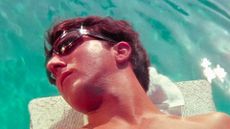 Dustin Hoffman wears sunglasses while lying beside a pool