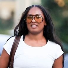 Sasha Obama wearing yellow tint sunglasses, a white crop top, and black long skirt in Los Angeles