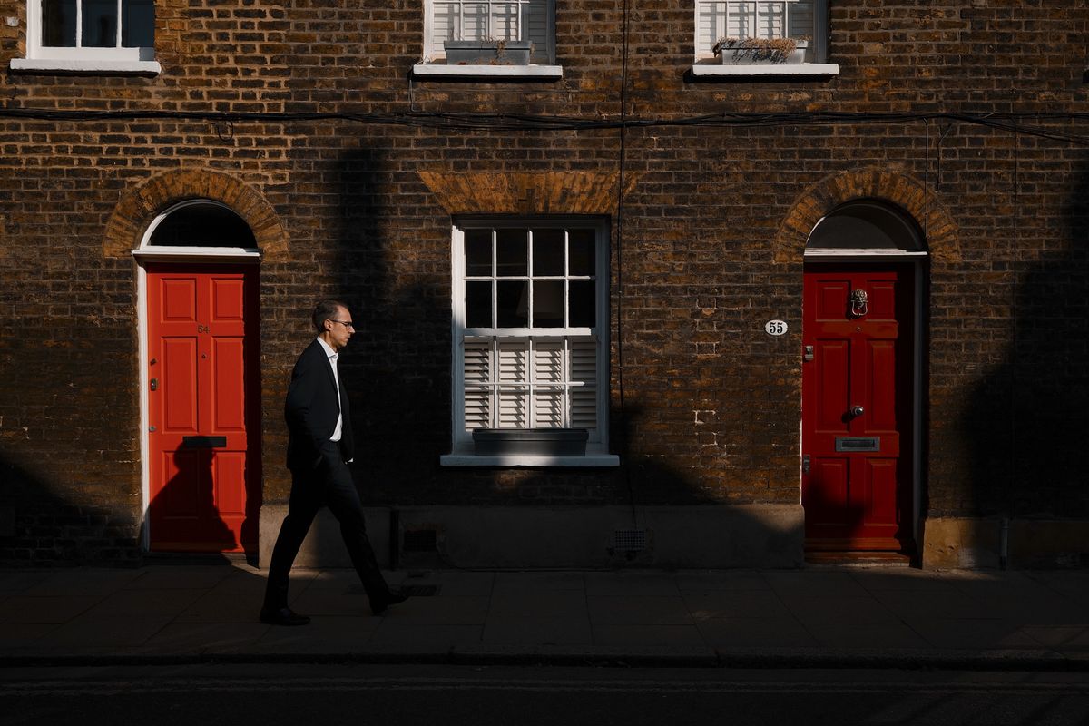 London street photo of people walking down old street in bright sunlight with strong shadows cast on the wall, taken with the Sigma BF camera and Sigma 35mm F2 DG lens
