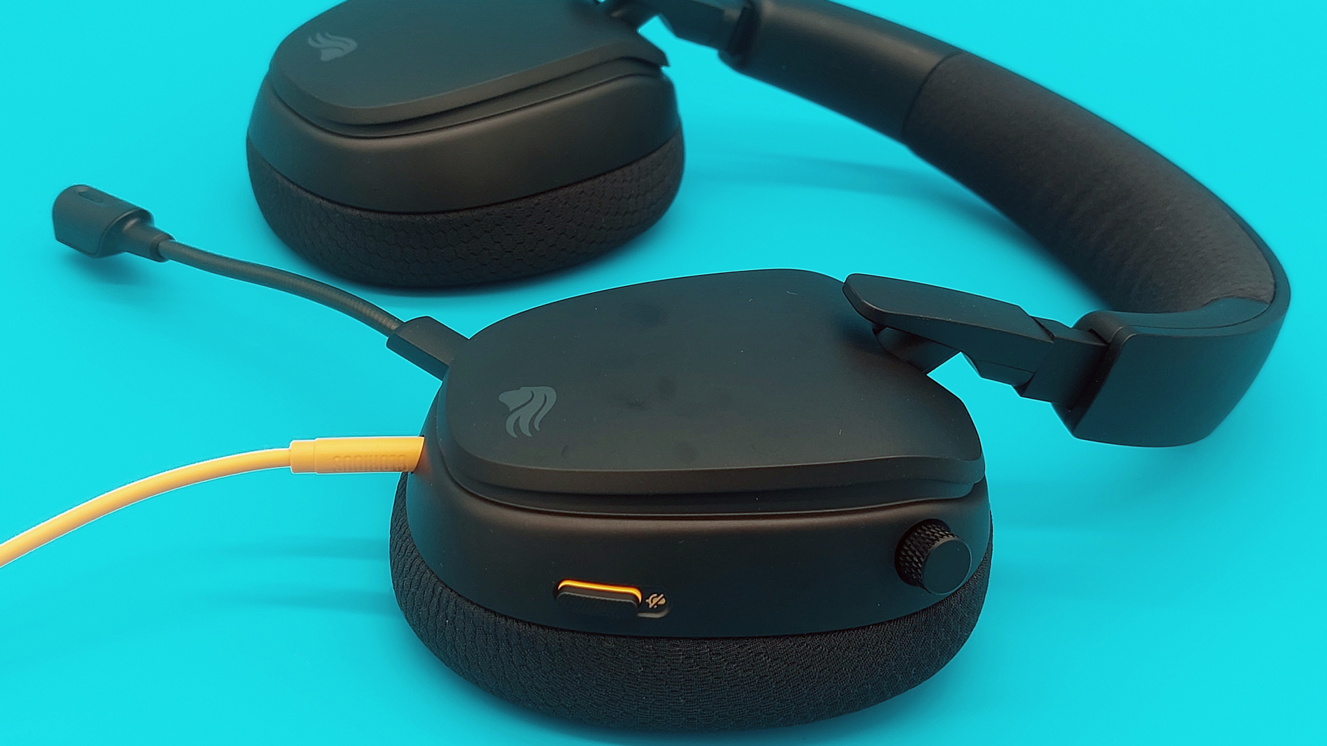 A Glorious GHS Eternal gaming headset on a blue background, showing the controls on the left earcup