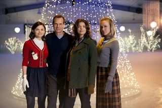 the cast of big love stands outside in the snow by a christmas tree of lights