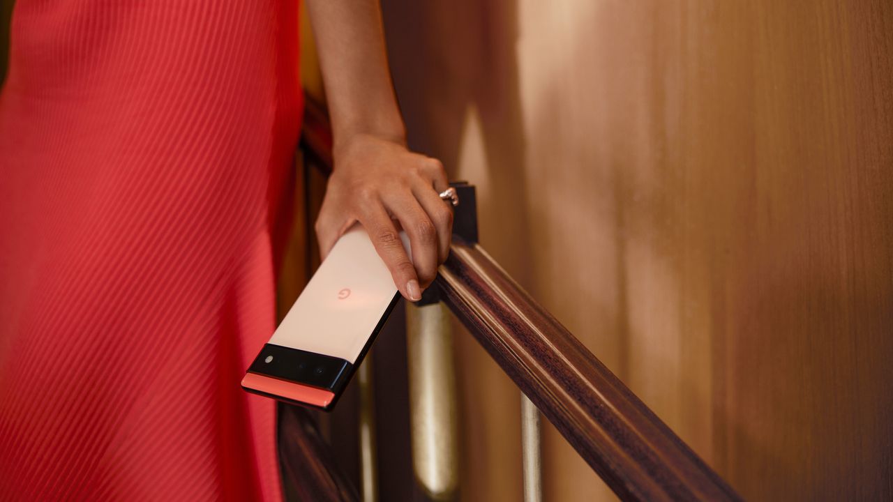 Google Pixel 6 Android phone being held by an adult female wearing a red dress