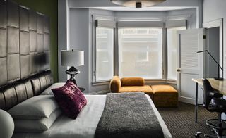 Bedroom with soaring ceilings, industrial light fixtures, and crushed velvet pillows
