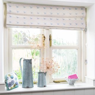 A window with roller blinds and dried flowers on the windowsill