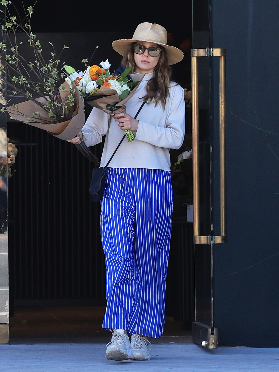 Elizabeth Olsen wearing blue striped pants and a straw hat