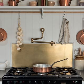 gold kicthen splashback idea behind black range cooker