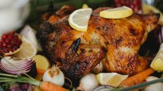 A close up image of roast turkey on a bed of vegetables