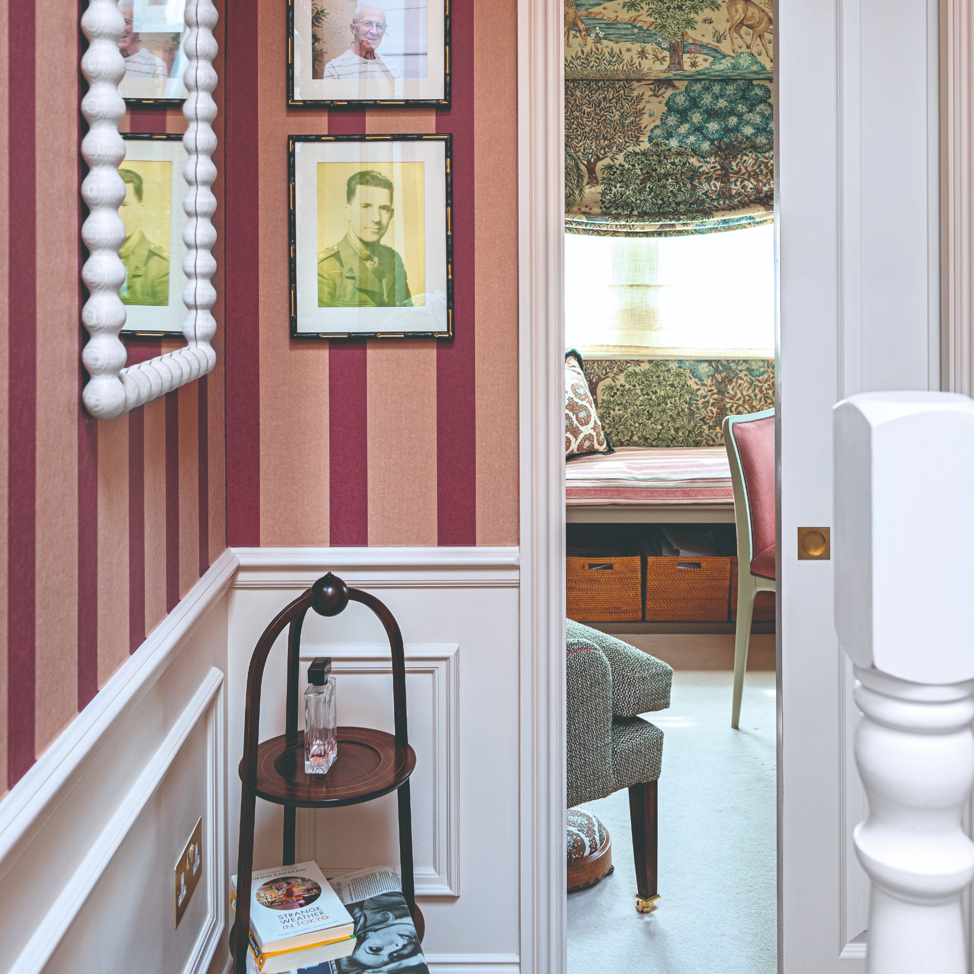 A hallway with a dado rail on the walls with the bottom half painted in white with panelling on top and the top half of the wall covered in a pink and red wallpaper