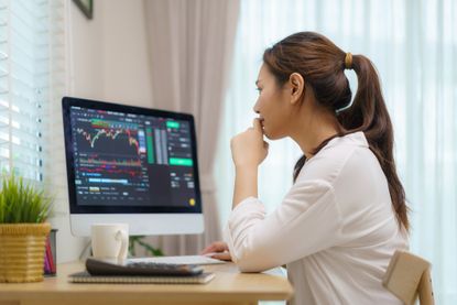 Woman sitting at a desk researching investments on the computer.