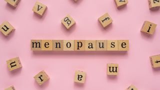 blocks spelling out menopause on pink background