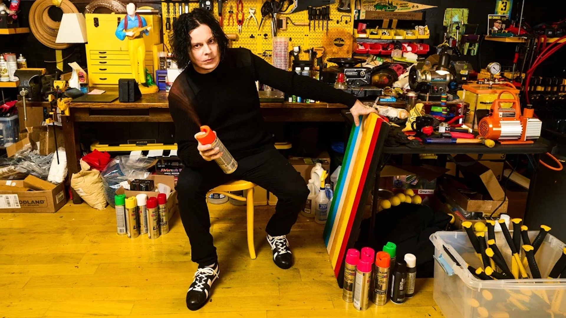 Jack White in his workshop holding spray paint 