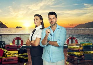 First Officer Kate Woods (Catherine Tyldesley) and Jack Grayling (Shayne Ward) stand on the deck of a ship with a beautiful Mediterranean sunset behind them. On the deck behind them are lots of suitcases wrapped in neon yellow tape marked 'crime scene do not cross'