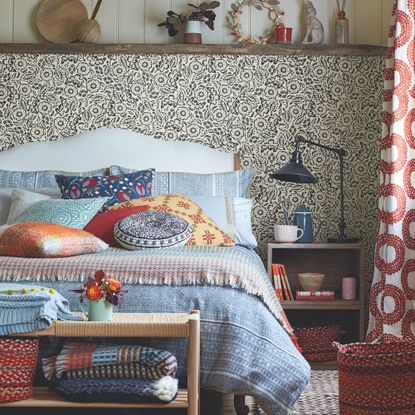 bedroom with colourful bedding and patterned wallpaper