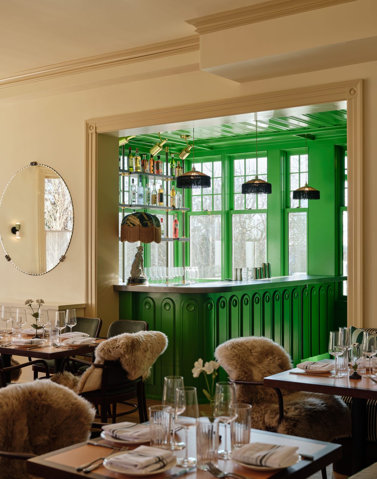 A cocooning, contemporary hotel features 1970s-inspired, plush, and puffy furniture, including upholstered modular sofas, shearling-topped chairs, and leathery chaise longue, sculptural lighting, and wooden tones mixed with vibrant greens.