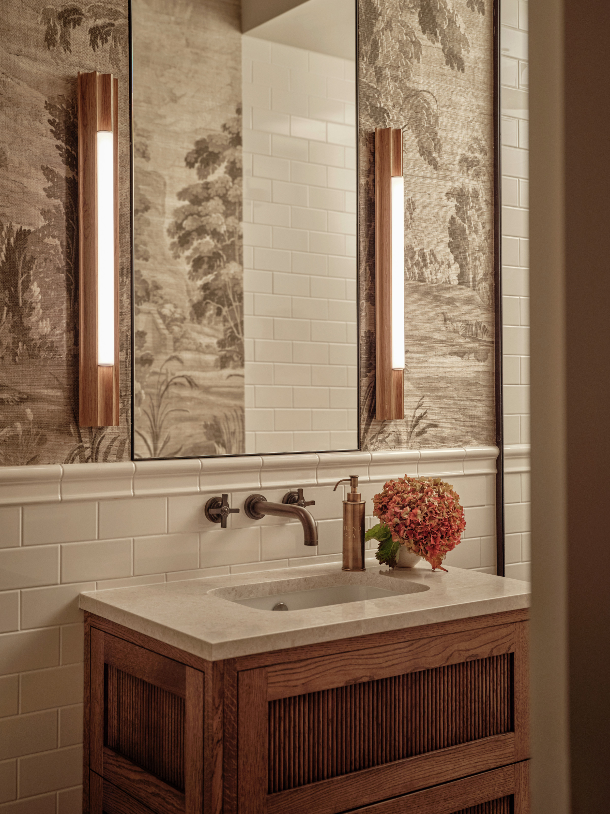 Bathroom with wood vanity, marble countertop, white metro tiles and grey and white nature mural