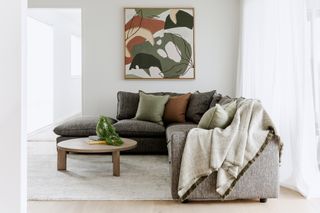 A grey sofa with decorative cushions and throw