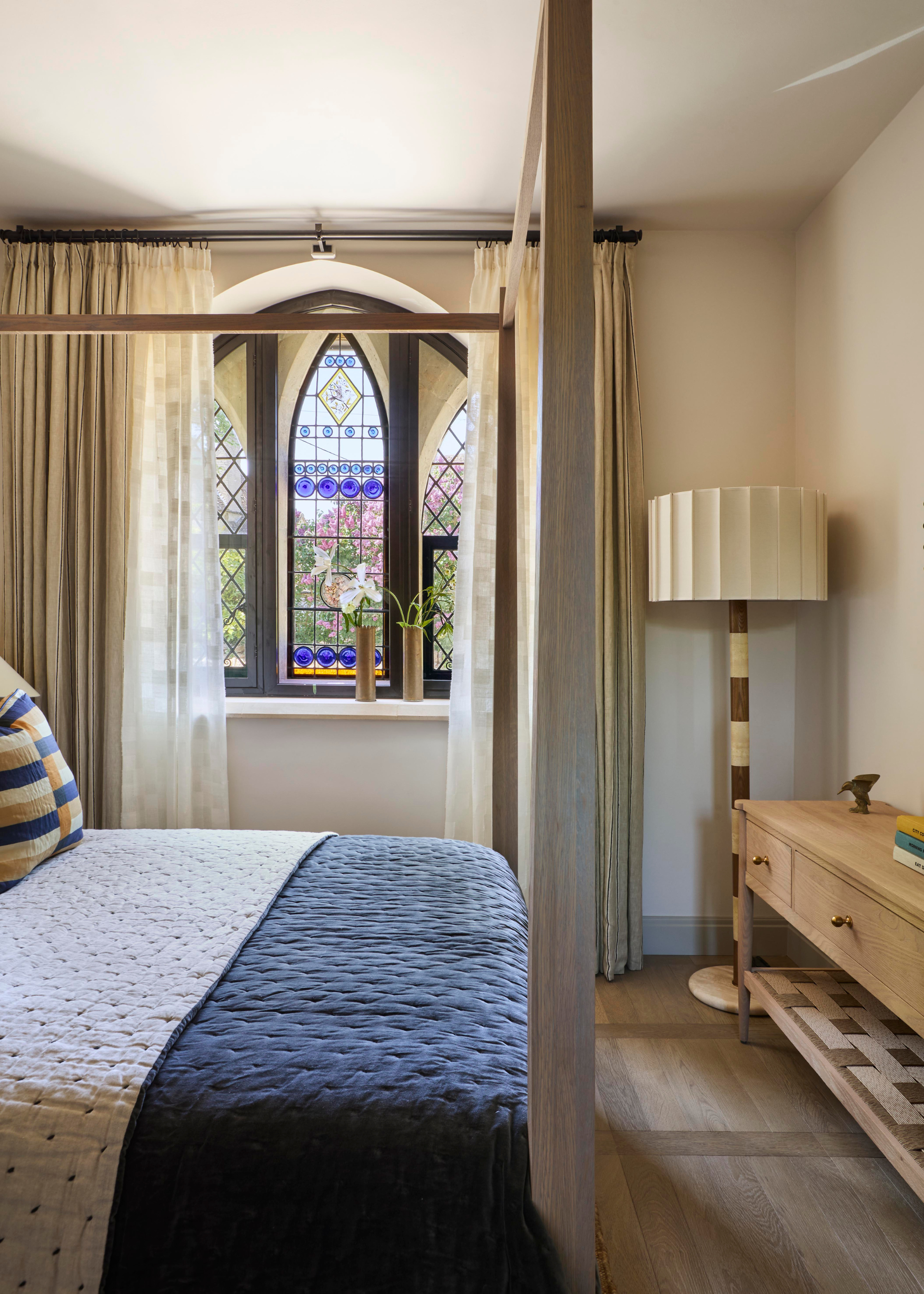 converted chapel bedroom with original arched windows and a four poster bed
