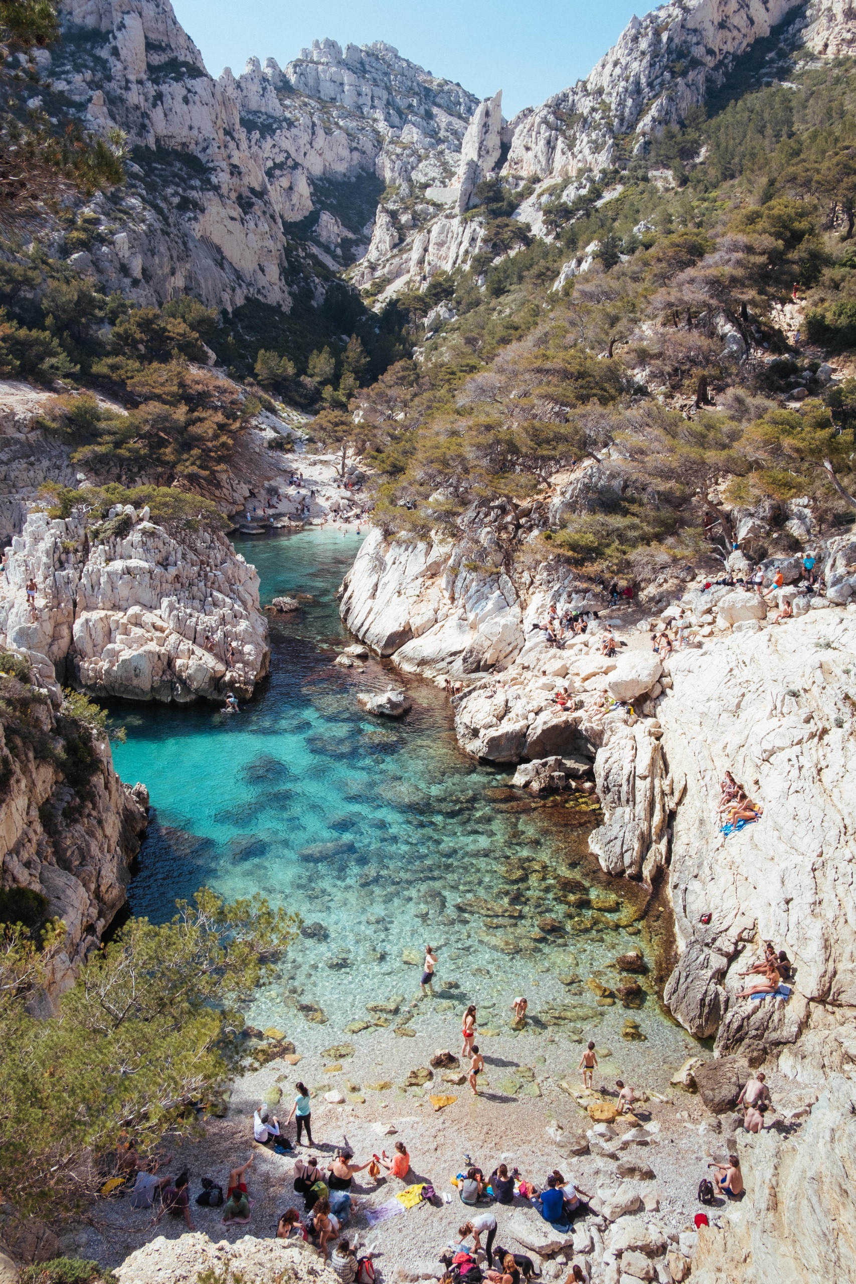 People resting on the sand on a rocky beach in Calanques National Park in southern France