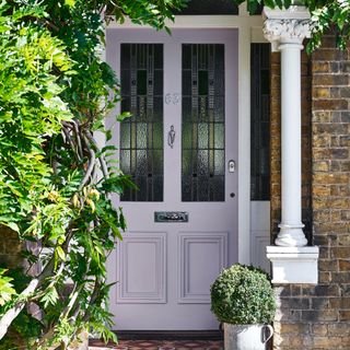 Lavender front door of period property surrounded by shrubs