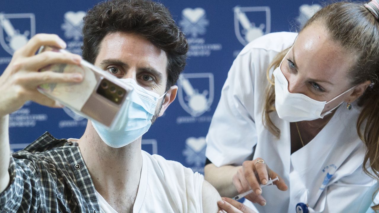 An Israeli man snaps a selfie while receiving his vaccination in Tel-Aviv