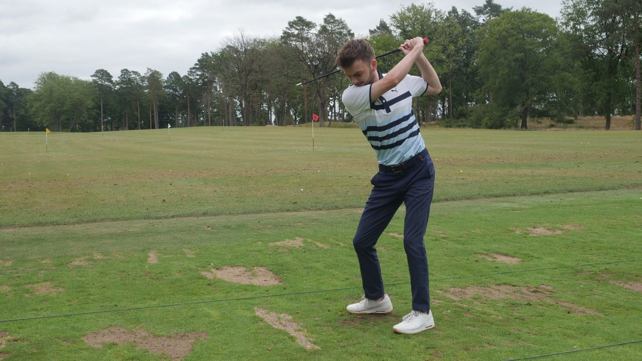 A golfer swining on a driving range with the SuperSpeed C Club