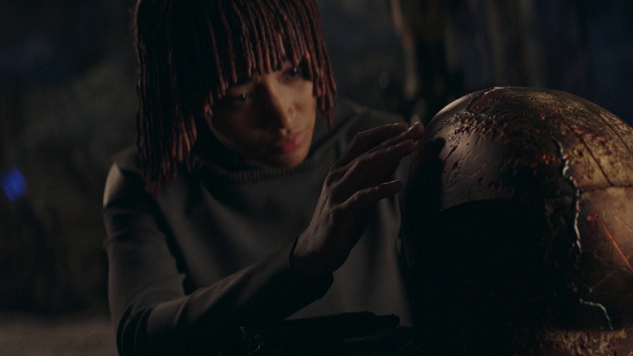 A young woman carefully inspects a cracked full-face helmet.