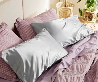 Gray silk pillowcases against pink bedding.