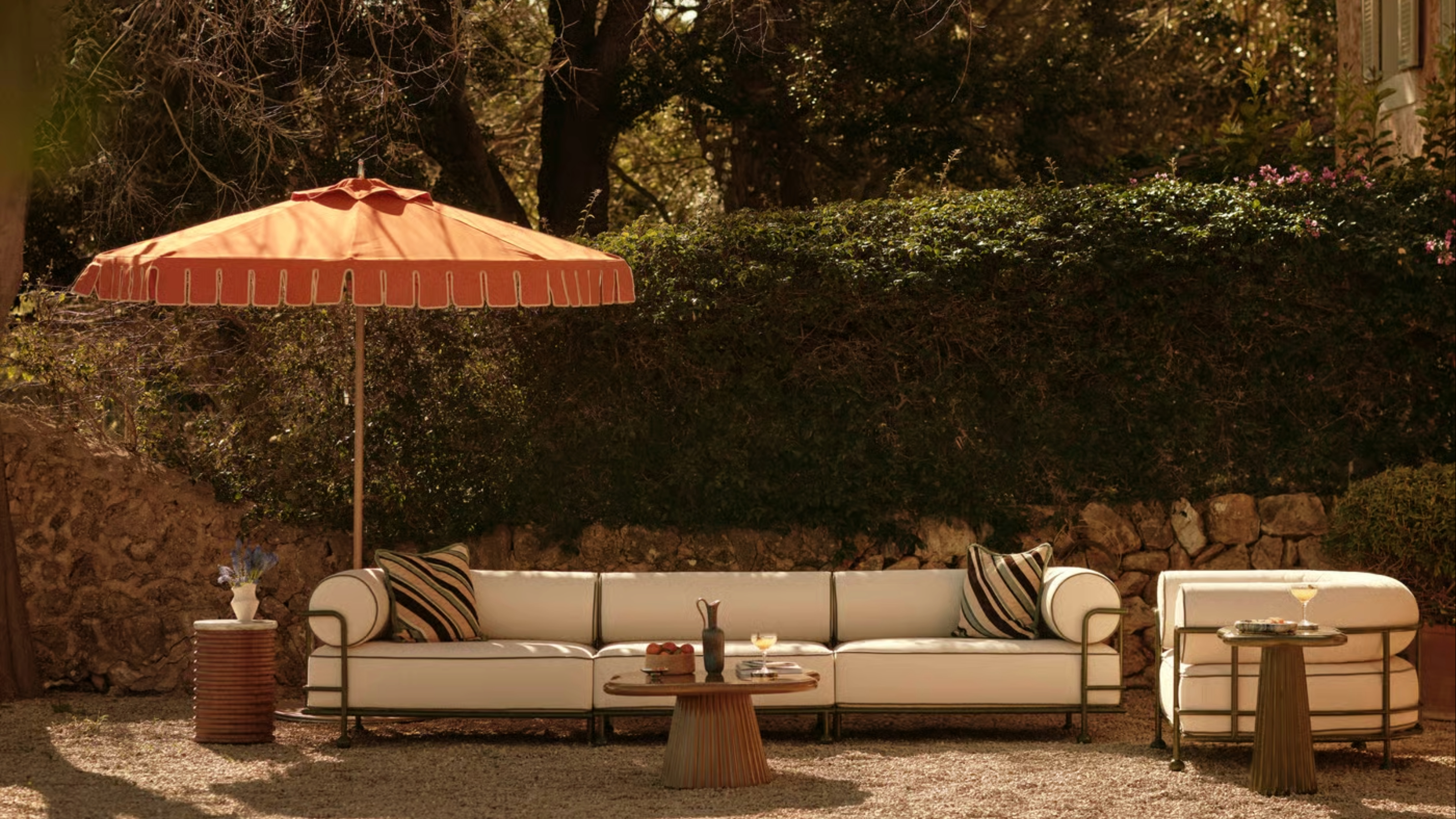 A garden with curved oudoor sofa and armchair, plus rounded side tables
