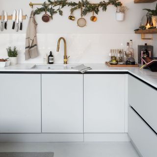 kitchen sink area with gold mixer tap and garland on the wall