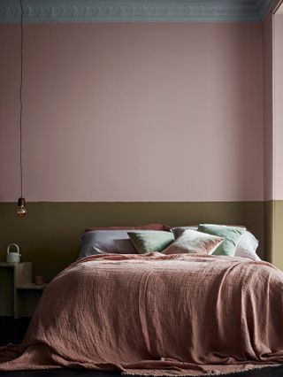 Block painted bedroom in pink and musty olive with low hanging decorative bulb and waffle texture bed throw