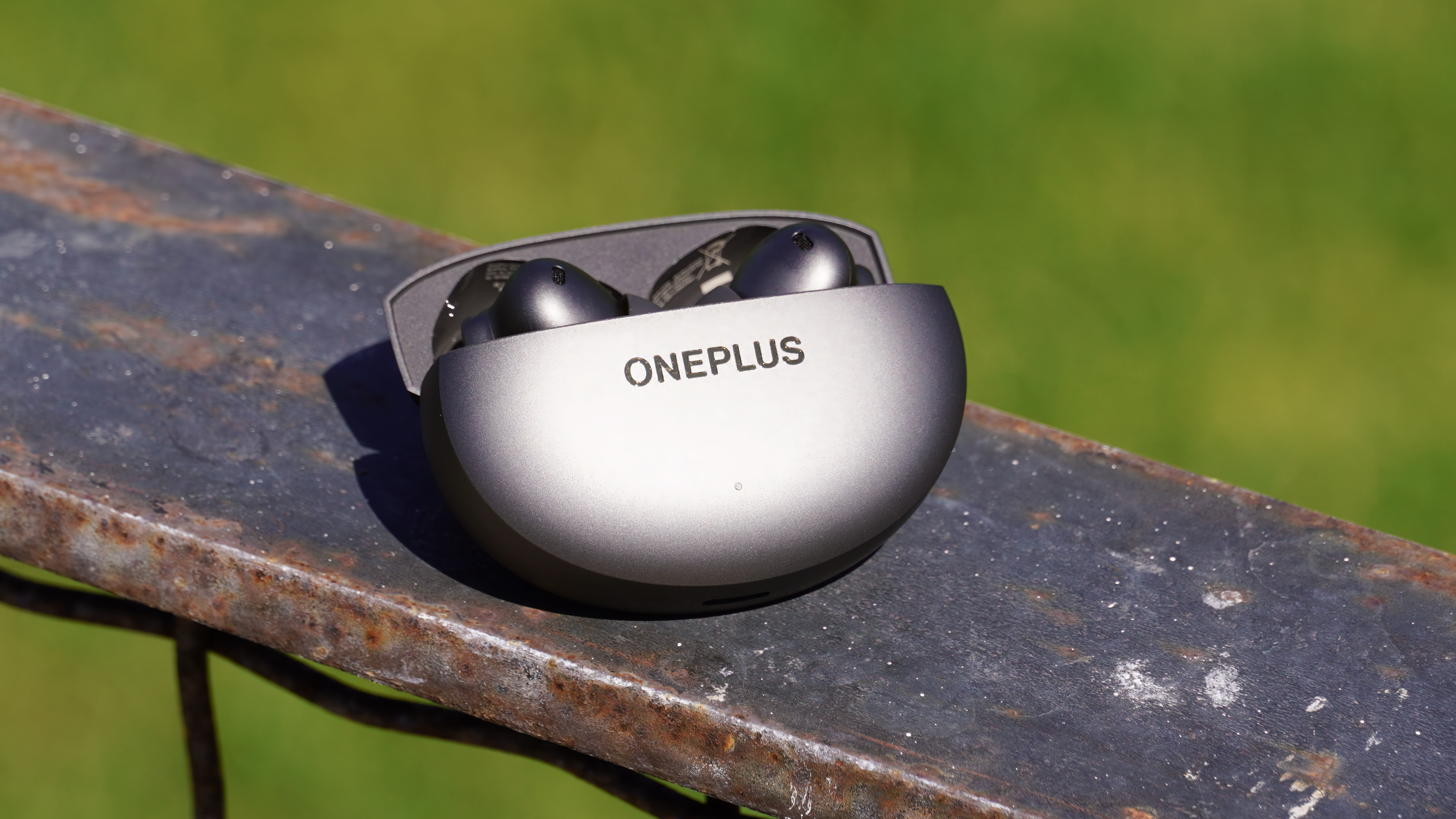 The OnePlus Buds 4 in Storm Gray on a ledge.