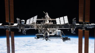 a T-shaped space station floats above Earth