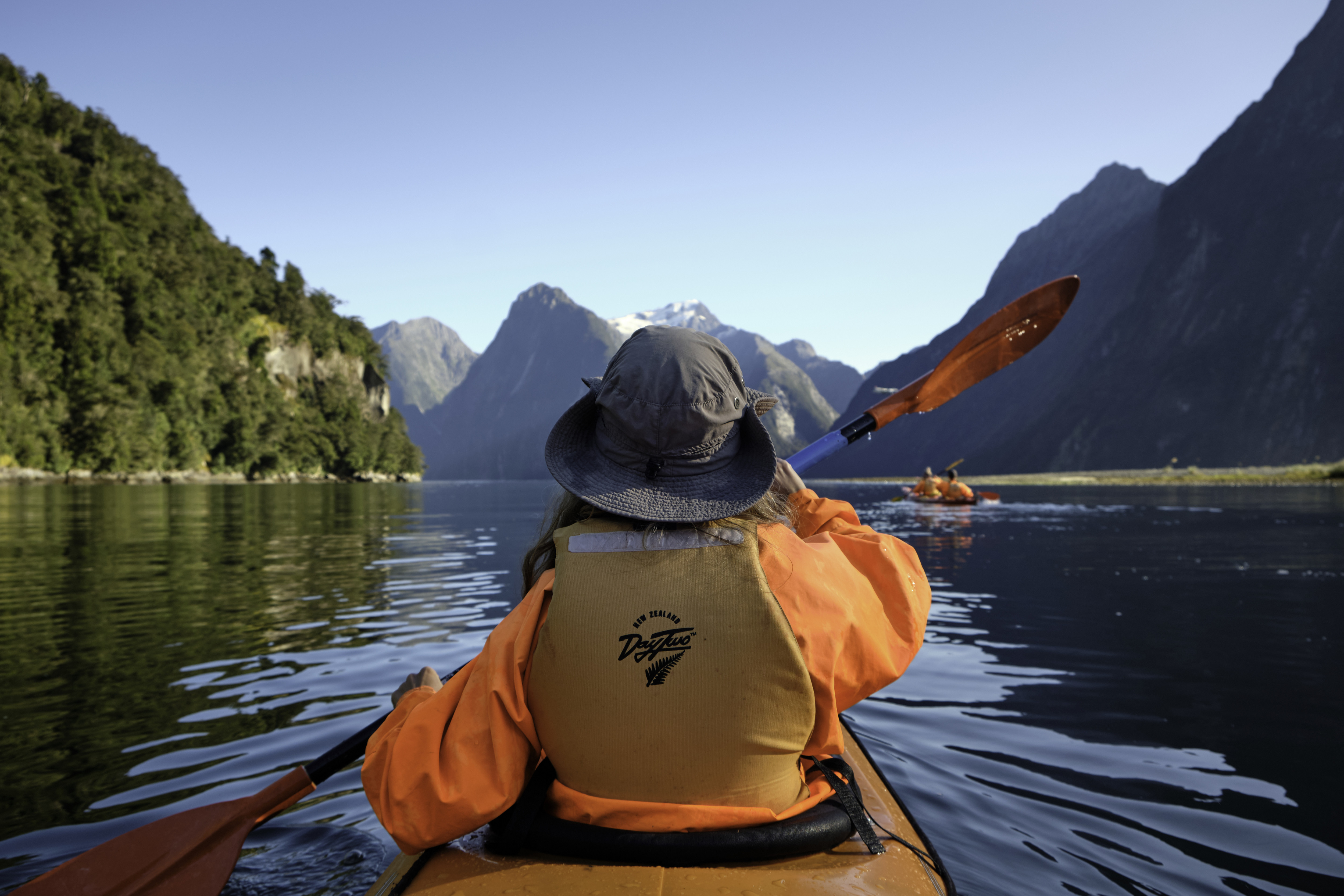 A woman kayaks through Milford Sound in New Zealand