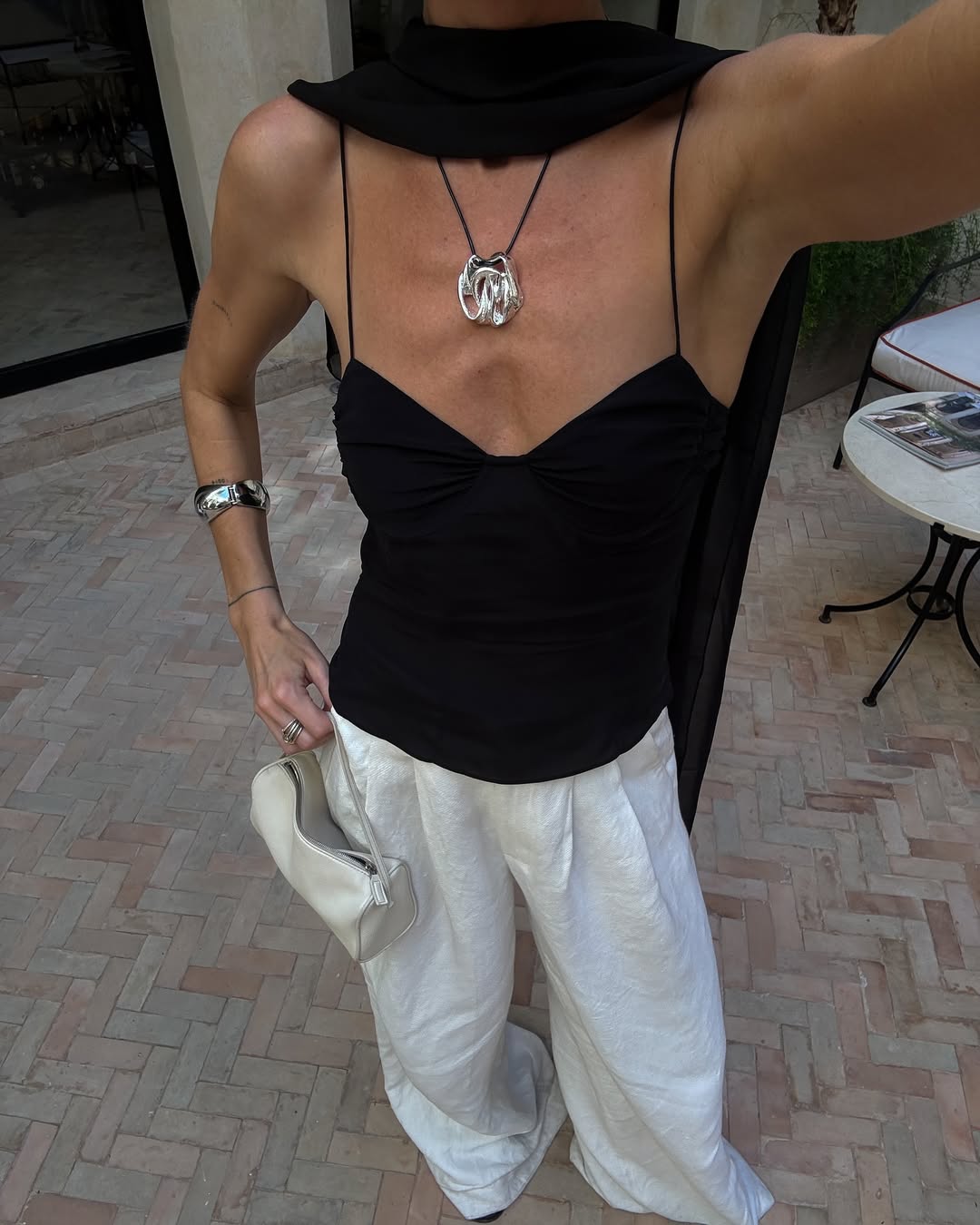 fashion influencer in black strappy top and white trousers