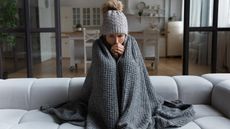 Woman dressed up in hat with blanket at home