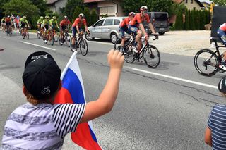 A fan waves as the peloton passes by at the Tour of Slovenia