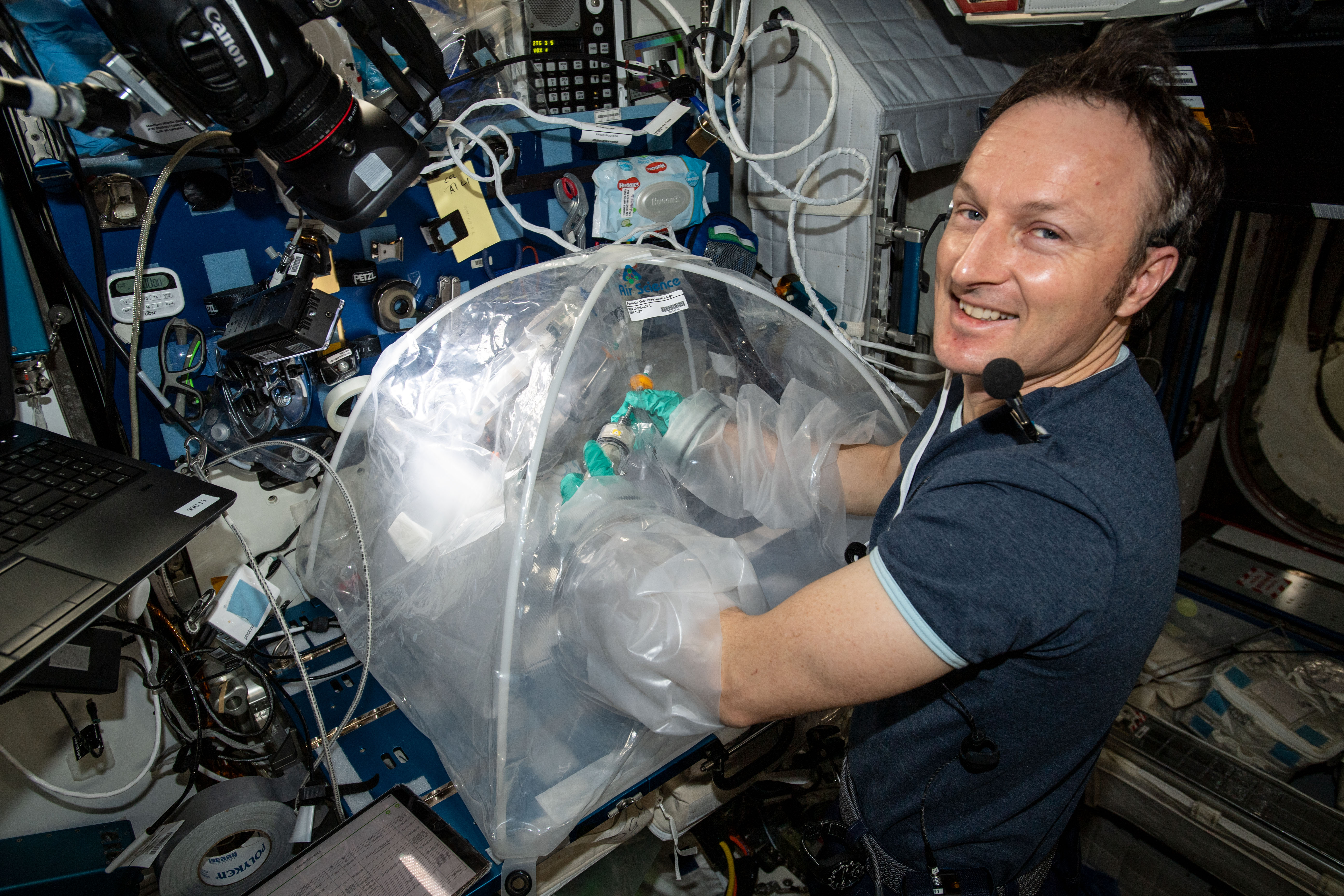 NASA Space Technology an astronaut with their hands in a box on the space station