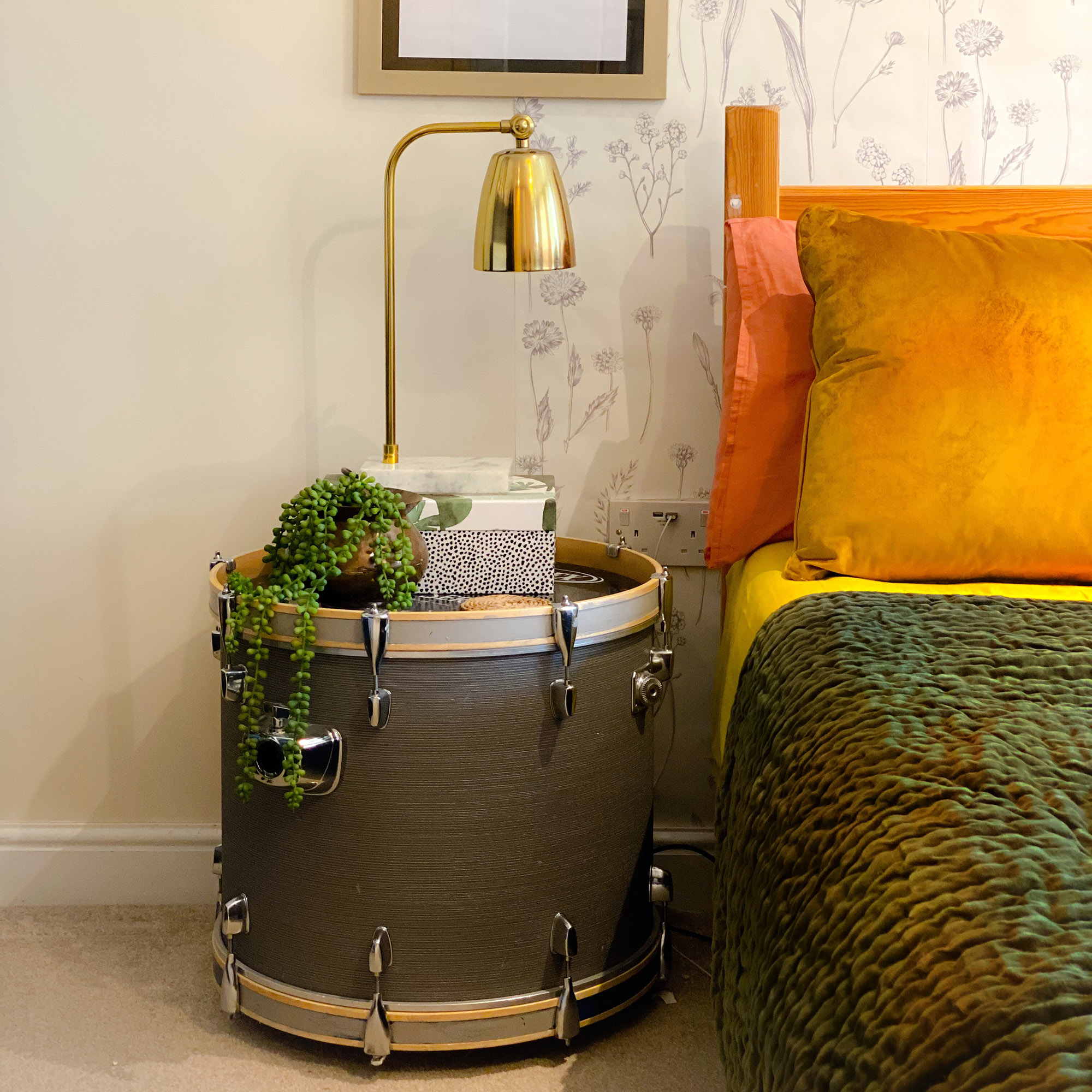 bedroom with drum as a bedside table and a gold light on it
