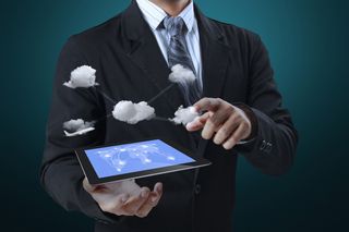 A man in a suit interacts with clouds seemingly coming out of a tablet computer.