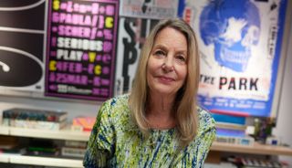 image of Paula Scher in front of posters of her work